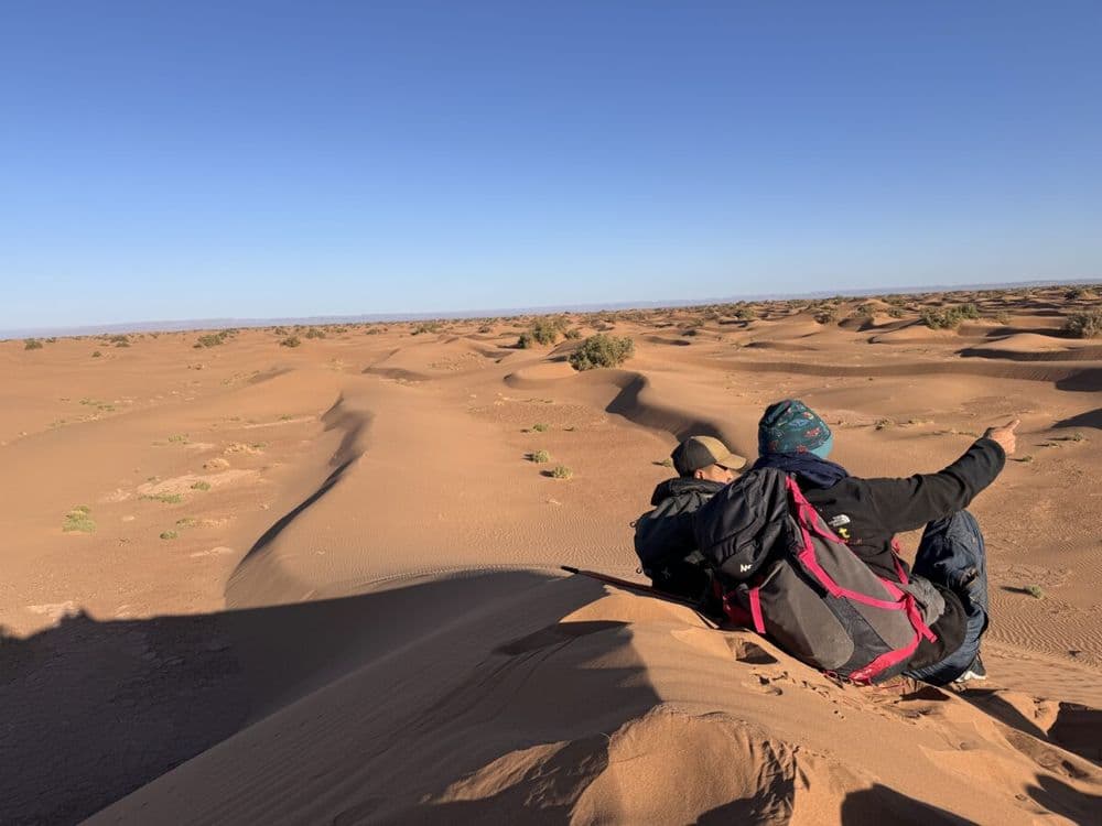 Deelnemer kijkt uit over de duinen van de Sahara